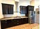 Gourmet kitchen featuring stainless steel appliances, granite countertops, dark cabinets, and modern fixtures at 2051 Sandy Garden Ln, Winter Garden, FL 34787
