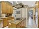 A kitchen island features an electric cooktop, granite counters, and a stainless steel vent hood at 213 N Monterey Isle, Longwood, FL 32779