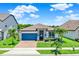 Charming single-story home featuring a blue garage door, well-manicured lawn, and vibrant landscaping at 2390 Standing Rock Cir, Oakland, FL 34787