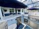 Outdoor kitchen with bar, grill, refrigerator and seating under blue umbrellas at 2390 Standing Rock Cir, Oakland, FL 34787