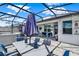 Inviting outdoor seating area featuring an umbrella, screened enclosure, and stylish decor at 2390 Standing Rock Cir, Oakland, FL 34787