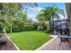 Lush backyard featuring a brick-paved patio, verdant lawn, manicured hedges, and a screened enclosure, perfect for outdoor enjoyment at 2418 Ridgemooor Dr, Orlando, FL 32828