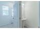 Clean, simple half bath features a pedestal sink, tiled flooring, and natural light from the window at 3028 Water Sprite St, Orlando, FL 32808