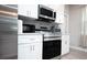 Modern kitchen with stainless steel appliances, white cabinetry, and gray backsplash at 309 E 13Th St, Apopka, FL 32703