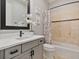 Bathroom features gray vanity, floral decor, a framed mirror and a shower with tile surround at 3535 Lake Sarah Dr, Orlando, FL 32804