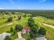 Stunning aerial view of a home nestled on a lush golf course, surrounded by mature trees at 36730 Oconee Ave, Eustis, FL 32736