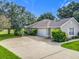 Exterior view of home with well-maintained lawn, mature trees, and a two-car garage at 36730 Oconee Ave, Eustis, FL 32736