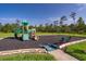 Community playground with swings, slide, and green safety ground cover surrounded by a lush green lawn at 3943 Crawley Down Loop, Sanford, FL 32773