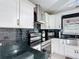 Modern kitchen featuring stainless steel appliances, sleek black backsplash, and white cabinetry at 4160 Packard Avenue, St Cloud, FL 34772