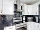 Updated kitchen featuring stainless steel appliances, white cabinets, and stylish black tile backsplash at 4160 Packard Avenue, St Cloud, FL 34772