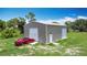 Gray metal outbuilding boasts both a roll-up door and side door, parked with a red car at 4160 Packard Avenue, St Cloud, FL 34772