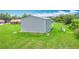 A gray metal outbuilding on a green lawn next to a house under a blue sky at 4160 Packard Avenue, St Cloud, FL 34772