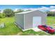 Metal storage outbuilding with roll-up door on manicured lawn at 4160 Packard Avenue, St Cloud, FL 34772
