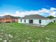 View of the home's backyard featuring grass and a weathered concrete patio with a home in the background at 5125 Pine Needle Dr, Mascotte, FL 34753