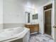 Well-lit bathroom featuring a tub, single sink vanity, and a walk-in shower with glass doors at 5125 Pine Needle Dr, Mascotte, FL 34753