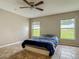 Sunlit bedroom with a ceiling fan, two windows, and tile flooring at 5125 Pine Needle Dr, Mascotte, FL 34753