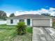 Charming single-story home featuring an attached garage, a green front door, and a well-maintained lawn at 5125 Pine Needle Dr, Mascotte, FL 34753
