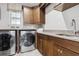 Laundry room boasts wooden cabinets, stone countertops, and modern washer and dryer units at 617 Canopy Estates Dr, Winter Garden, FL 34787