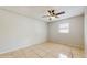 A tile-floored bedroom with a ceiling fan, window, and neutral-colored walls at 624 American Heritage Pkwy, Orlando, FL 32809