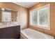 Bright bathroom with double vanity and soaking tub underneath window with blinds at 7145 Lake Dr, Orlando, FL 32809