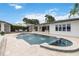 An outdoor pool and spa with fountains, surrounded by a stone patio and tropical landscaping at 7145 Lake Dr, Orlando, FL 32809