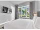 Bedroom with large window overlooking palm trees, featuring a wall-mounted television at 7740 Sandy Ridge Dr # 124, Reunion, FL 34747