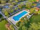 Aerial view of a community pool surrounded by lush landscaping, palm trees, and parking with tennis courts at 7918 Esta Ln, Orlando, FL 32827