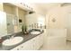 Bathroom featuring double sinks, vanity, soaking tub, and a glass-enclosed shower at 8093 Indian Creek Blvd, Kissimmee, FL 34747