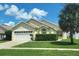 Charming single-story home with a well-manicured lawn, lush hedges, and a large palm tree providing shade at 8093 Indian Creek Blvd, Kissimmee, FL 34747
