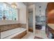 Bathroom with soaking tub, shower, tile floor and access to the main bedroom at 831 Royalwood Ln, Oviedo, FL 32765