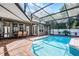 Screened-in pool area with a brick patio, an outdoor kitchen, and ample seating at 831 Royalwood Ln, Oviedo, FL 32765