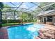 Screened-in pool area with lush landscaping, a spa, and a covered patio at 831 Royalwood Ln, Oviedo, FL 32765