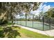 Well-maintained tennis court enclosed by a fence, with manicured lawns surrounding it at 831 Royalwood Ln, Oviedo, FL 32765