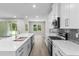 Modern kitchen with white cabinets, quartz countertops, stainless steel appliances and open floor plan at 136 N James Pl, Groveland, FL 34736
