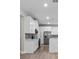 Modern kitchen with white cabinets, gray backsplash, stainless steel appliances, and wood-look flooring at 136 N James Pl, Groveland, FL 34736
