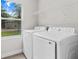 Well-lit laundry area with modern appliances, a window, and shelving for storage, creating an organized space at 136 N James Pl, Groveland, FL 34736