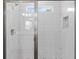 Glass enclosed shower featuring a rainfall shower head, a mosaic tile floor, and a built-in soap niche at 136 N James Pl, Groveland, FL 34736