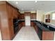 Kitchen featuring wood cabinets, black appliances, black countertops, tile backsplash, and tile floor at 14508 Cedar Branch Way, Orlando, FL 32824