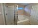 Bright bathroom featuring a glass-enclosed shower, soaking tub and a small window for natural light at 16631 Lazy Breeze Loop, Clermont, FL 34714