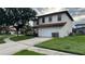Two story home featuring a white exterior, tile roof, two car garage, and a well manicured front yard at 16631 Lazy Breeze Loop, Clermont, FL 34714