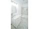 Elegant white bathroom features a marble-look floor, vanity with a marble countertop, and shower with marble-look surround at 19951 Quinlan St, Orlando, FL 32833