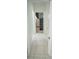 Hallway with white tile floors leading to a bedroom with a dresser and view of a window with curtains at 19951 Quinlan St, Orlando, FL 32833