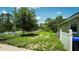 Side yard of property with a white fence and grassy area, with trees and a glimpse of the neighborhood at 19951 Quinlan St, Orlando, FL 32833