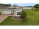 Single story stucco home featuring a well-manicured lawn and landscaping, including a picturesque lake view at 2400 Addison Creek Dr, Kissimmee, FL 34758