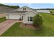Single story stucco home featuring a well-manicured lawn and landscaping, including a picturesque lake view at 2400 Addison Creek Dr, Kissimmee, FL 34758