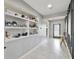 Inviting hallway with light tile floors, neutral paint, and decorative shelving at 2400 Addison Creek Dr, Kissimmee, FL 34758