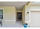 Covered front porch with a dark-colored front door, neutral stucco walls, and a light fixture at 2409 Martins Run, Tavares, FL 32778