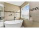 This bathroom boasts a soaking tub with a tiled wall, a modern glass shelving, and natural light at 2777 Monticello Way, Kissimmee, FL 34741