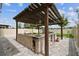 A covered outdoor kitchen is complete with BBQ, sink, refrigeration, and dining space at 2777 Monticello Way, Kissimmee, FL 34741