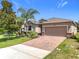 Beautiful one-story home featuring lush landscaping, a brick driveway, and neutral colors at 3744 Quaint Ln, Clermont, FL 34711